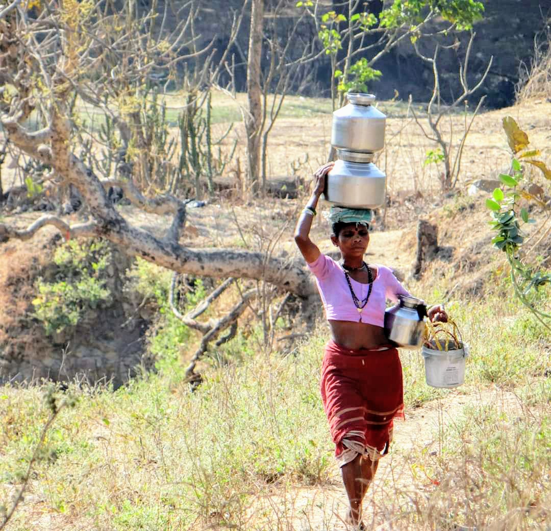 A woman carrying steel water pots home in rural India